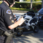 a motorcycle police officer writing a ticket at a stop.